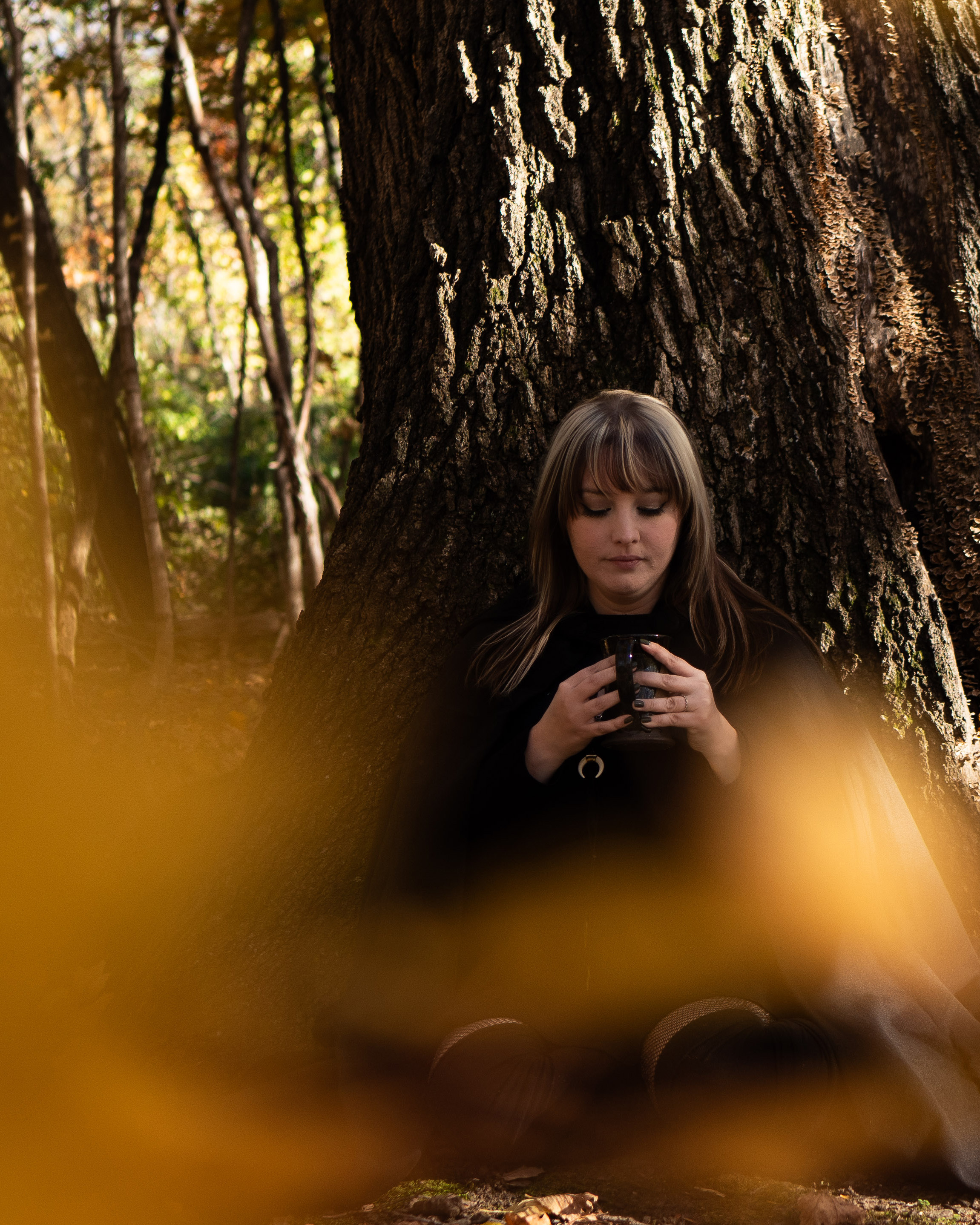woman dancing in the woods in a white dress with her hair flowing in front of her face. feminine and feral!
